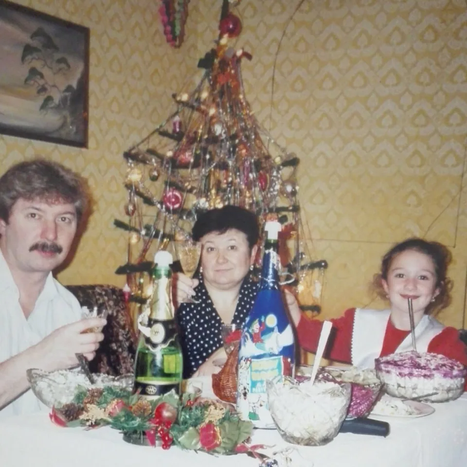 Ksenia als Kind mit ihrer Familie an einem festlich gedeckten Tisch